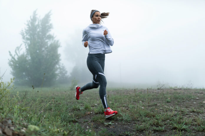 determined-female-runner-jogging-through-misty-filed-morning-copy-space